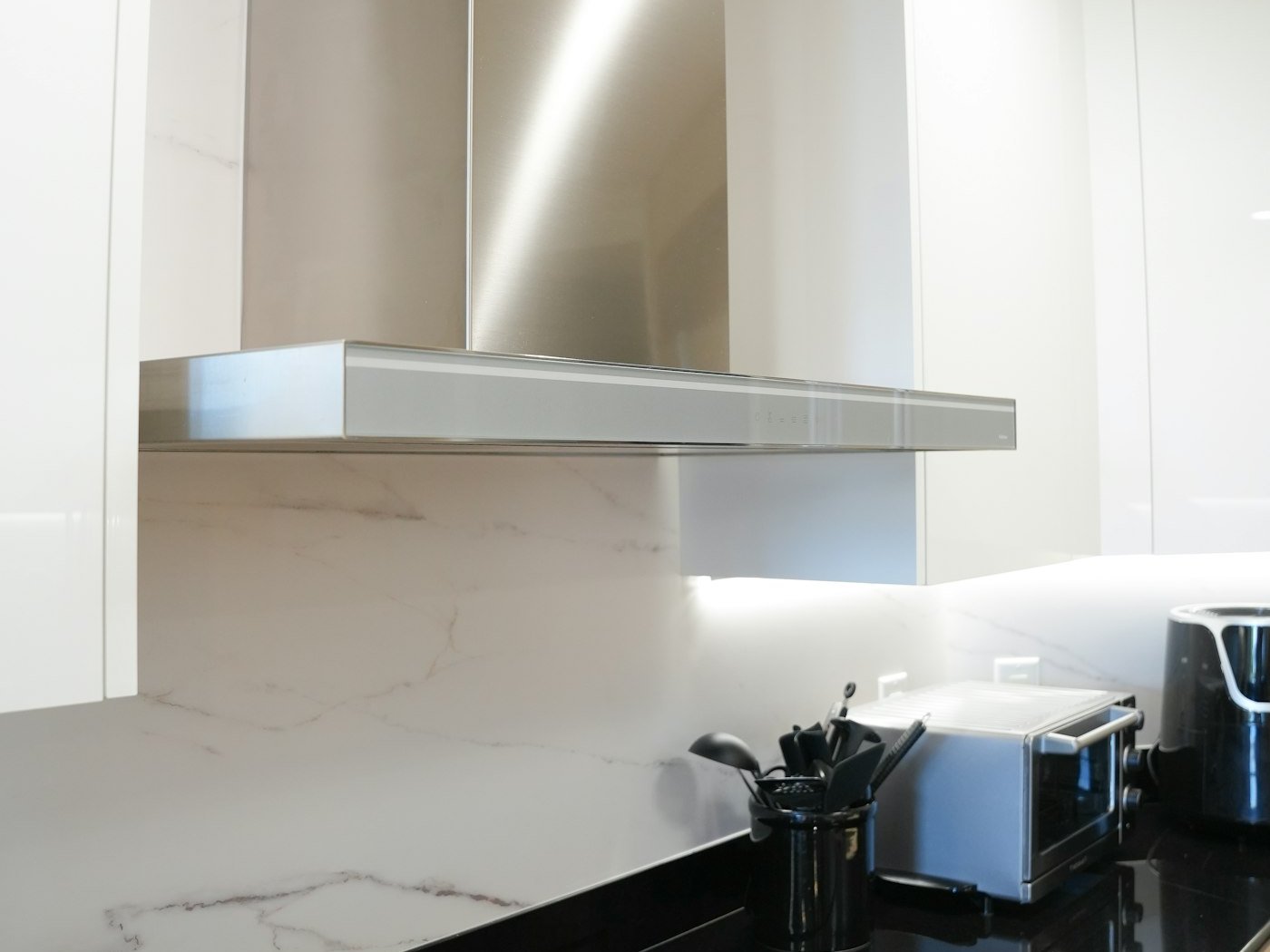 Stainless steel chimney cooker hood above a kitchen hob